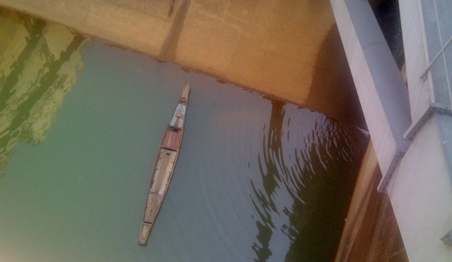 Wooden fishing boat floating next to the closed gate of the Pak Mun Dam.