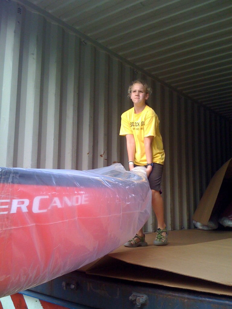 Miriam lifting and moving the canoes out of the container.